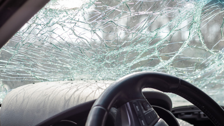 Damaged car window after an accident. Broken windshield as a result of an accident, inside view. Cabin interior details, view from the cab. Safe movement. Broken windshield. Glass crack and damage.