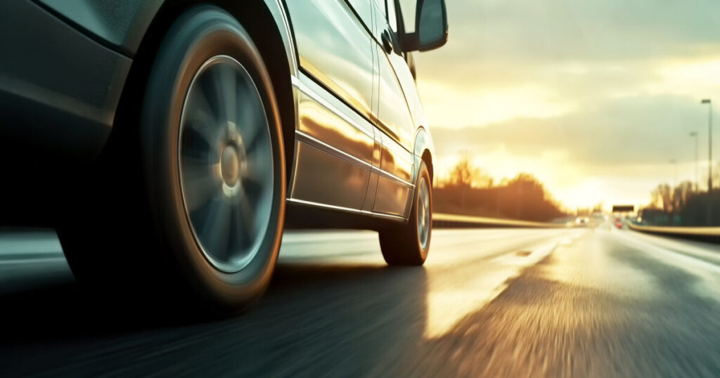 Car rushes along the highway at sunset , low angle side view