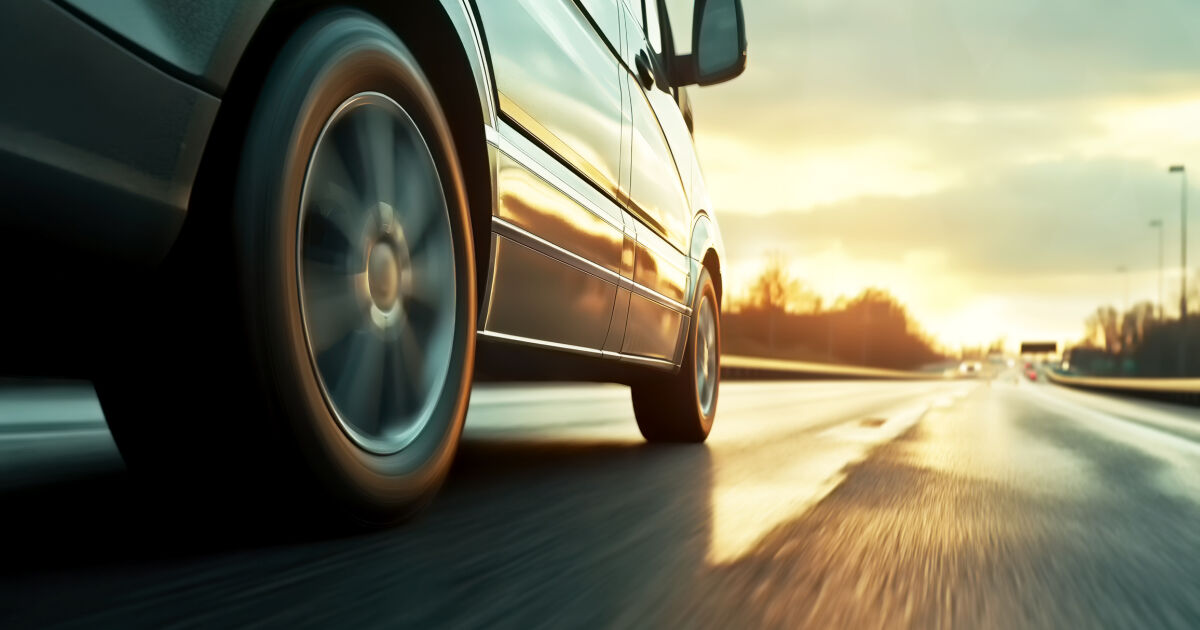 Car rushes along the highway at sunset , low angle side view