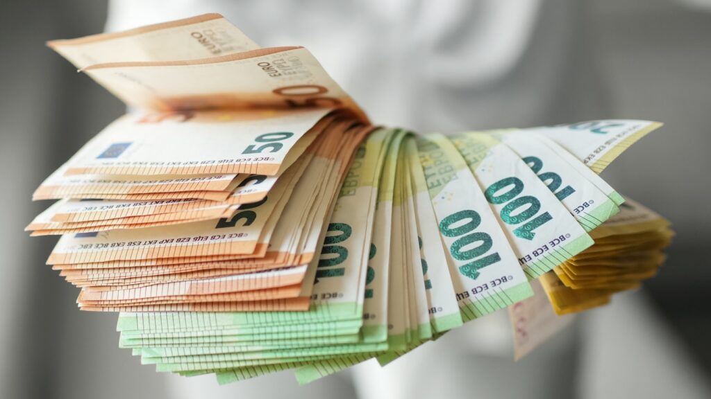 Hand holding large fan of euro banknotes in 50, 100, and 200 denominations, concept of abundance, wealth, success and financial prosperity