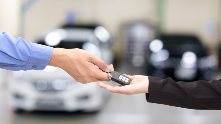 Young business women giving a key car in font of car.